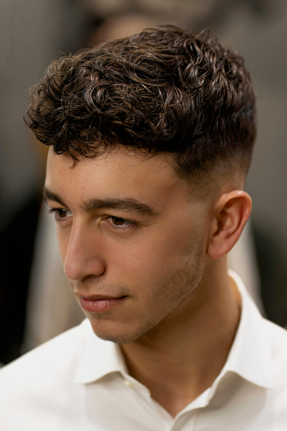 Barbero espolvoreando polvos voluminizadores Waverk UP en la raíz del cabello de su cliente para añadir textura, volumen y fijación ligera sin apelmazar.